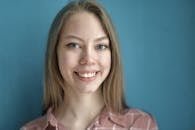 Cheerful blond haired blue eyed lady in casual wear toothy smiling at camera while standing against blue background